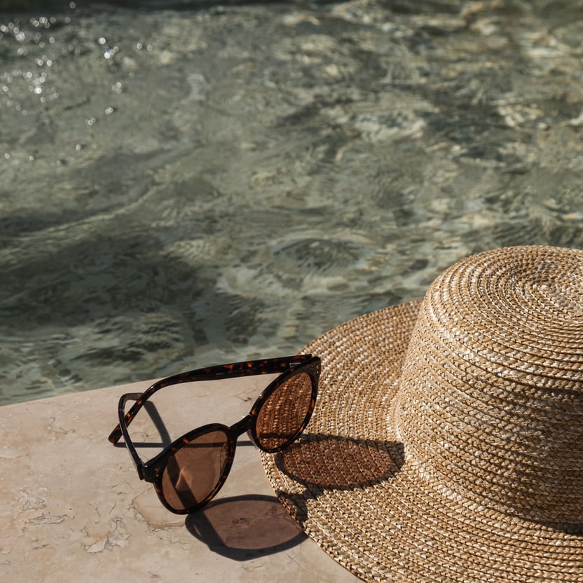 Sunglasses and Straw Hat on Swimming Pool Side  